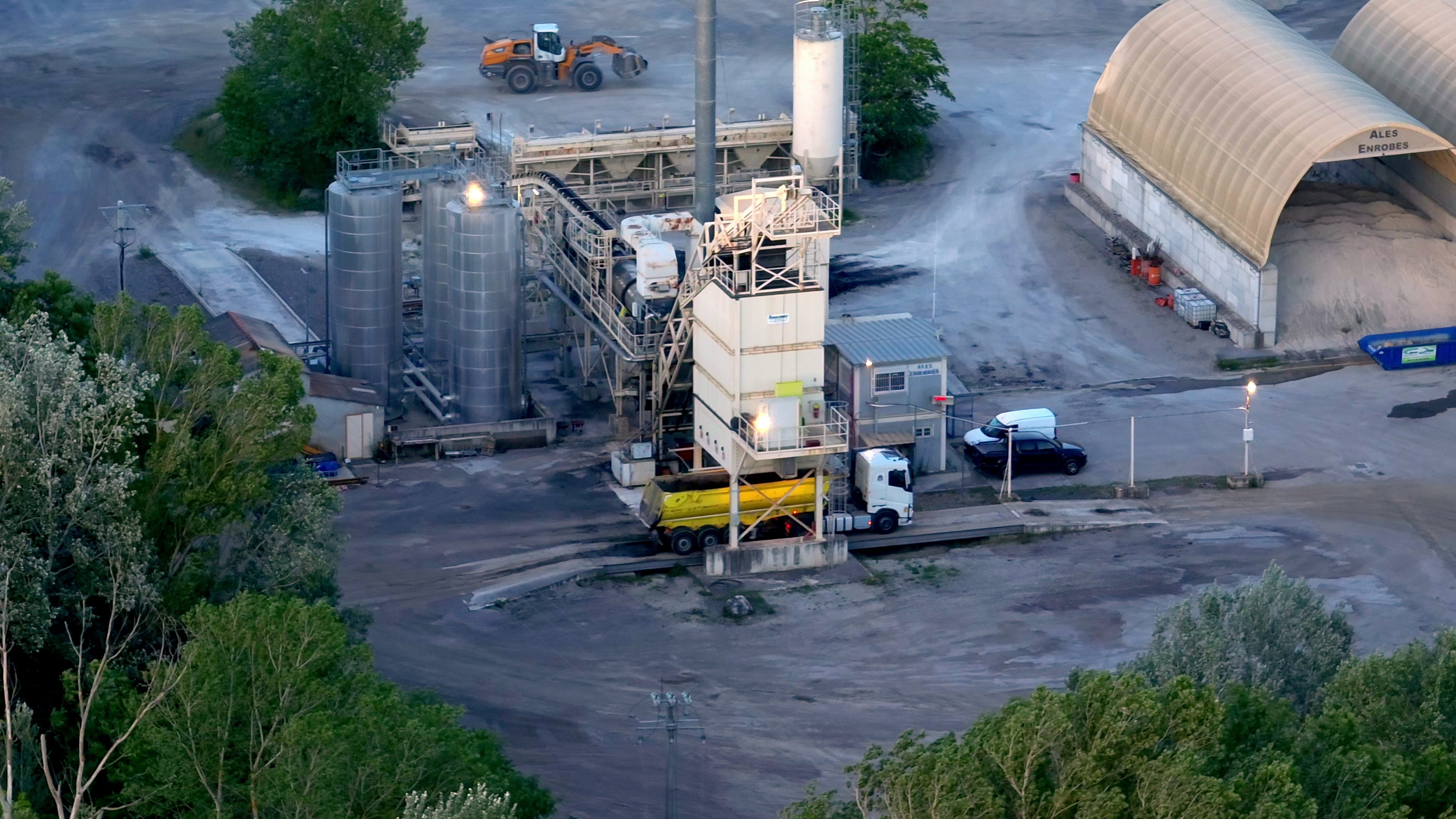 aerial shot of an industrial facility with silos, trucks, and machinery